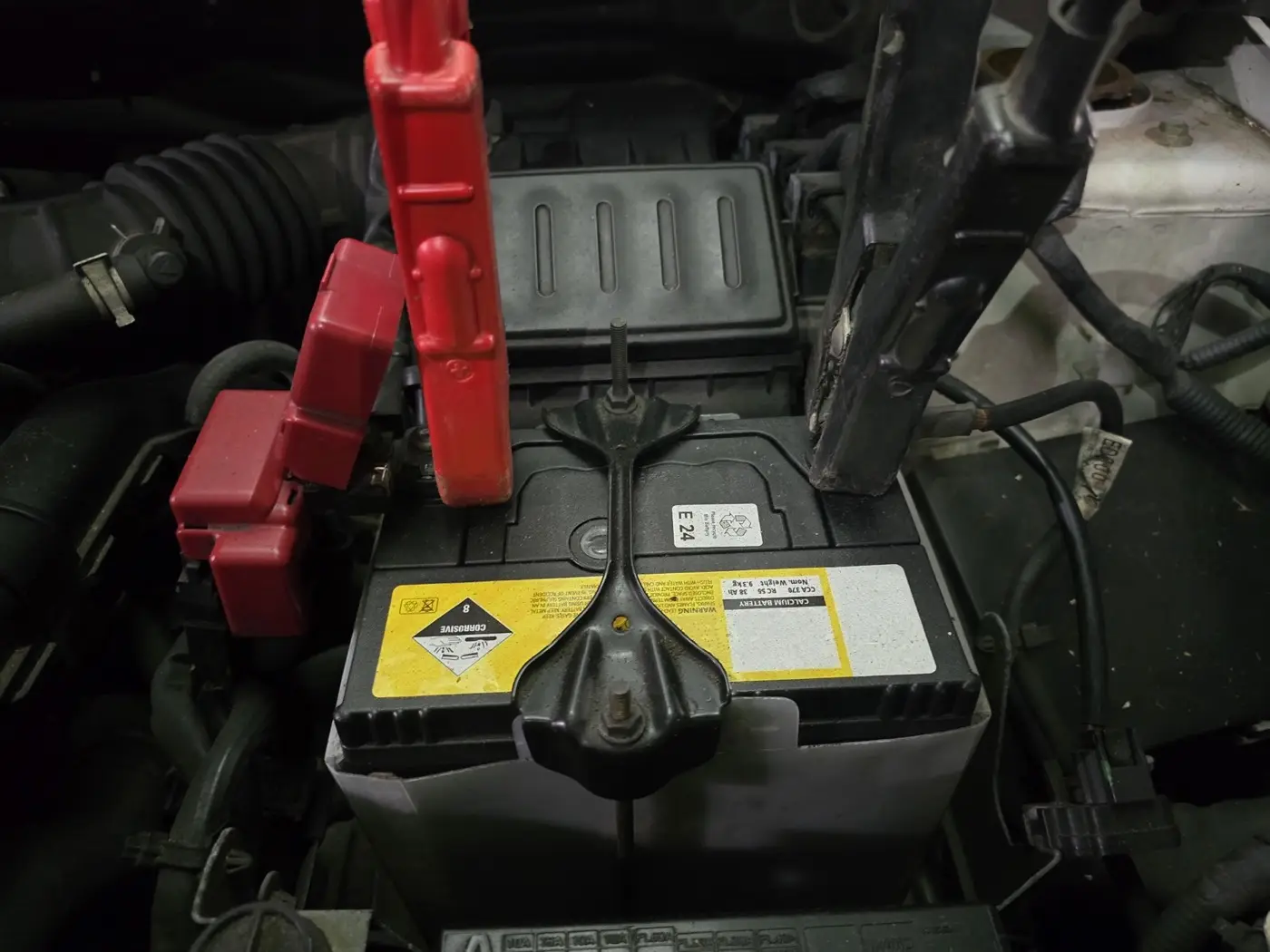 A car battery with jumper cables attached to the terminals.