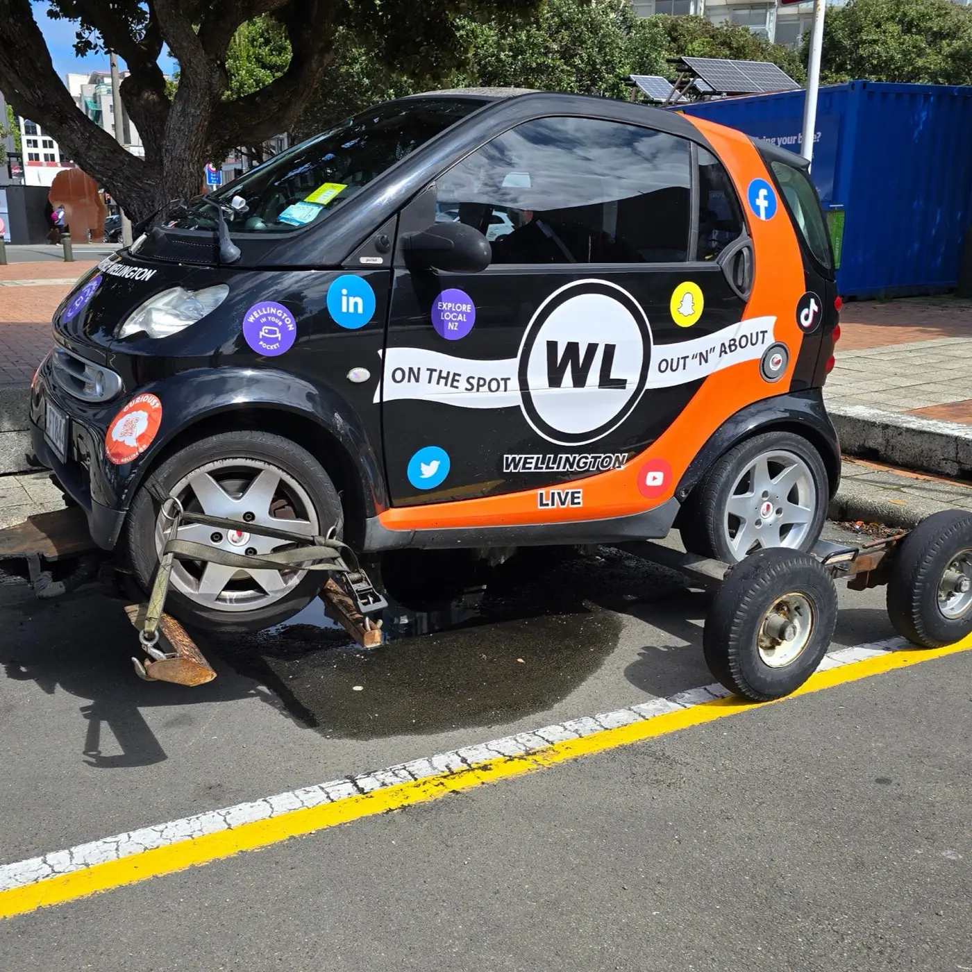 A car being lifted by a tow truck, with a dolly under the rear wheels.