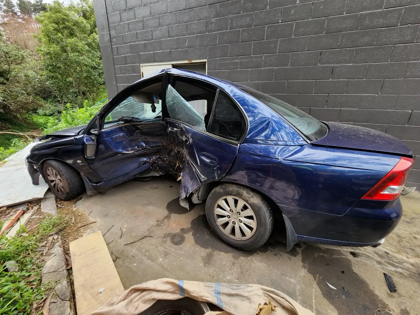 A blue car with heavy damage to the left side.
