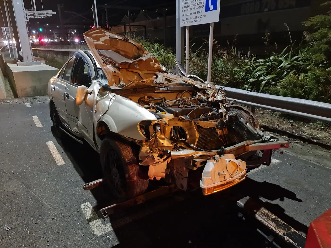 A heavily damaged vehicle with its front wheels lifted, bonnet peeled back over the windscreen.