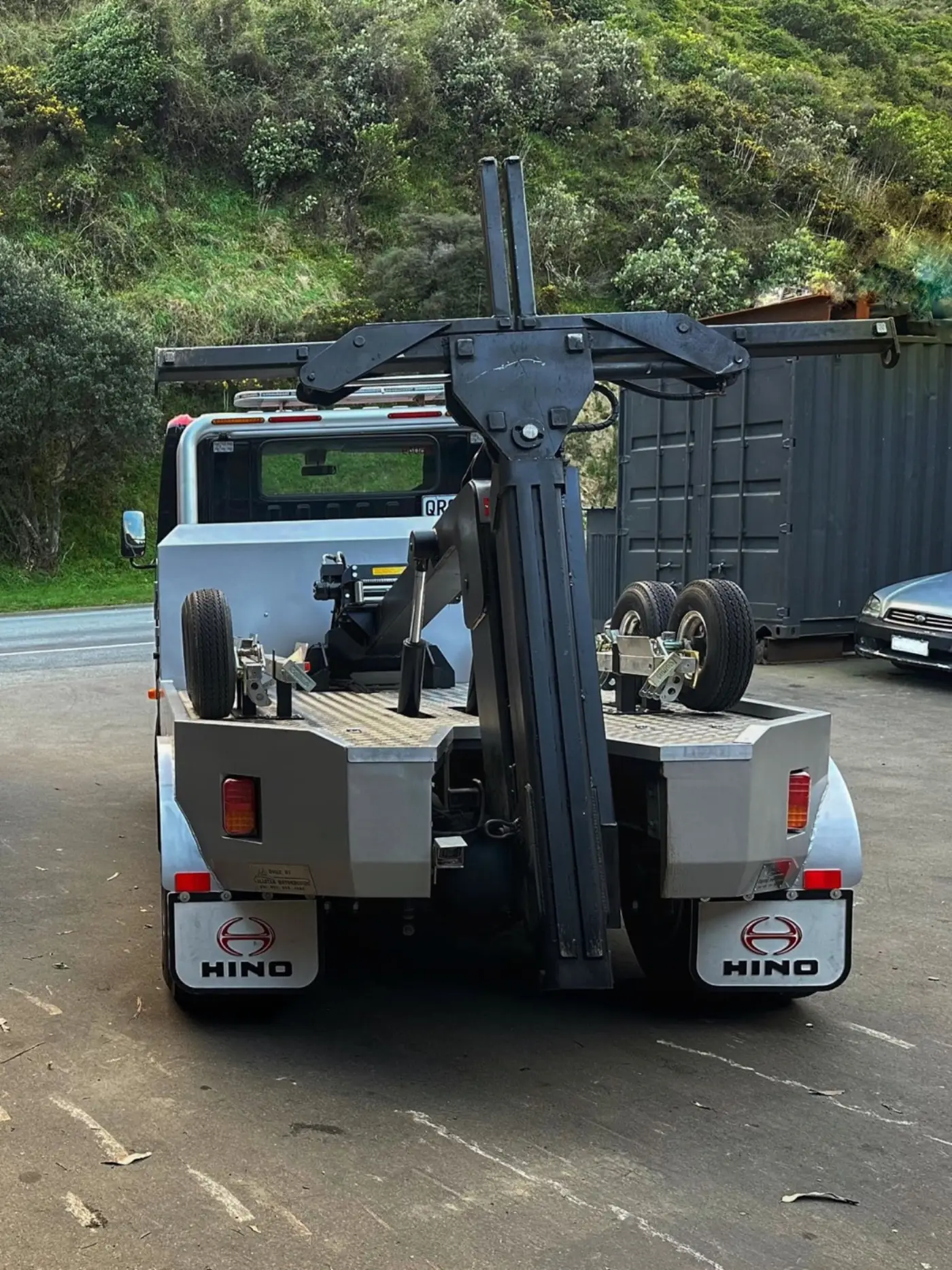 A hybrid-powered tow truck photographed from the rear, showing its hydraulic-powered wheel lift.
