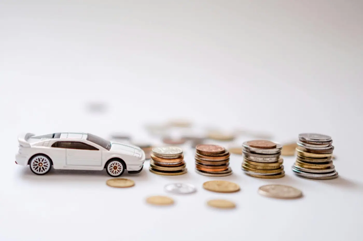 A toy sports car near a pile of coins.